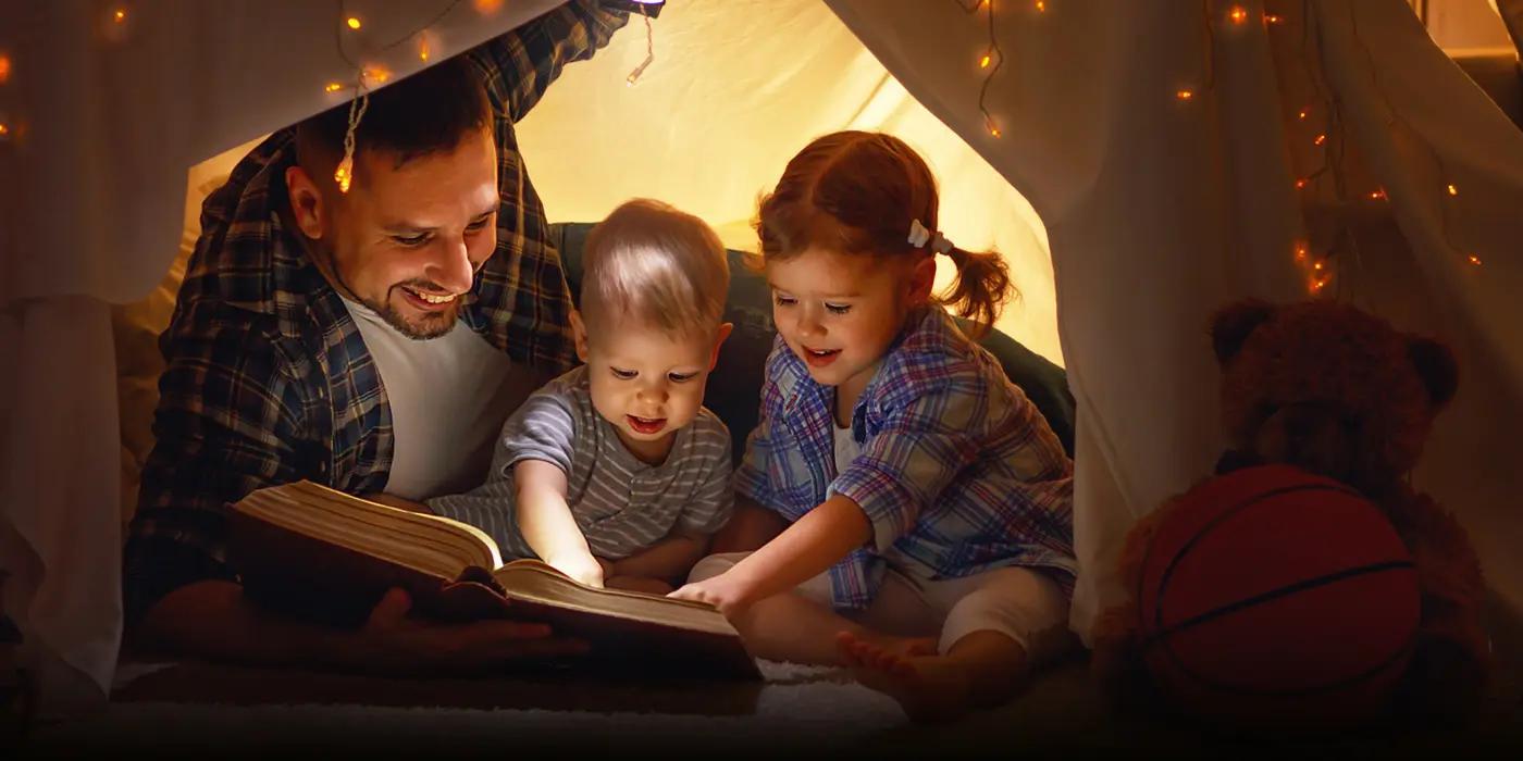 Family in a tent looking at a book
