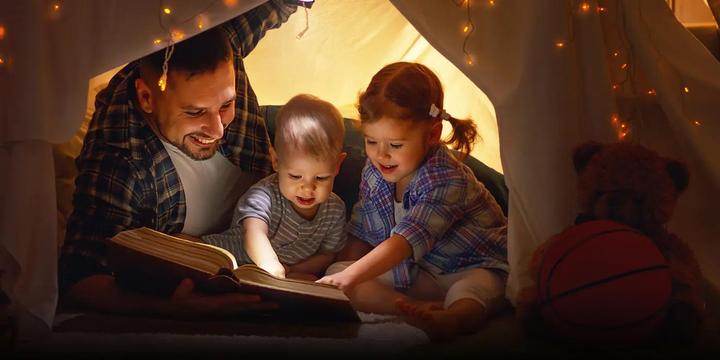 Family in a tent looking at a book