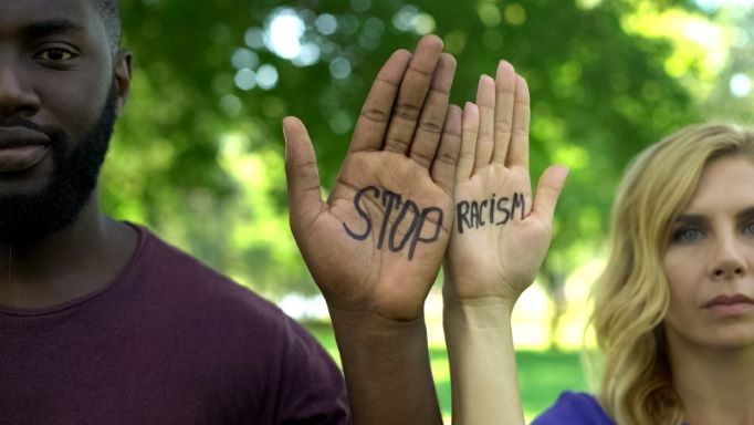 Man and woman with Stop Racism writing on their palms